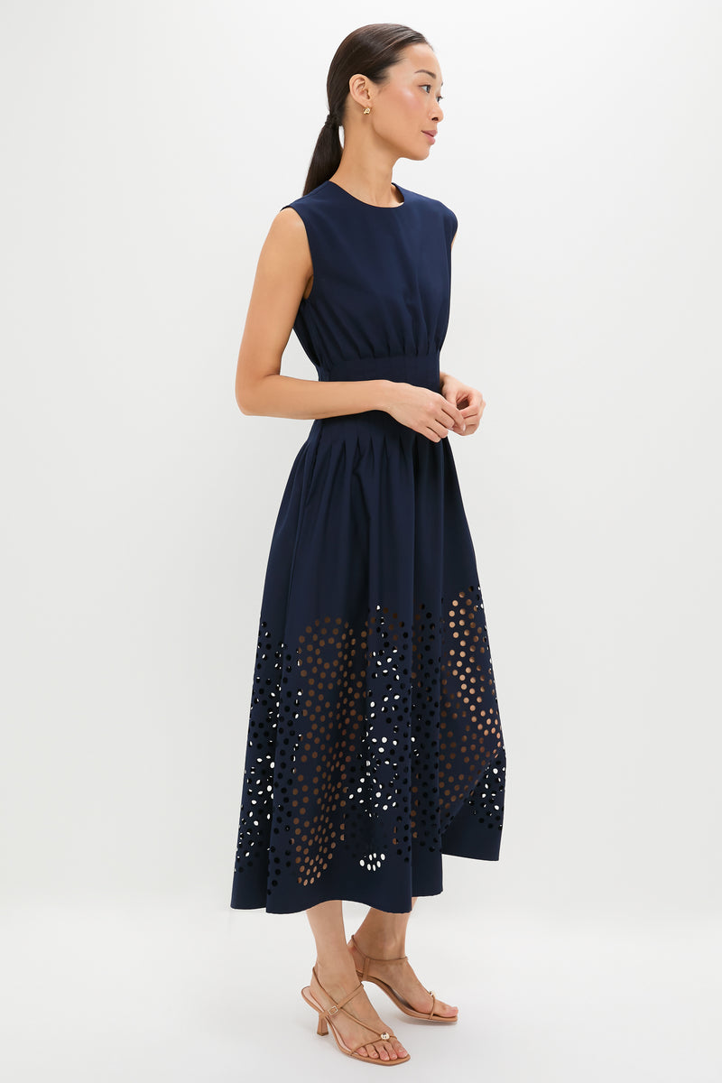Woman in profile wearing the Navy Astrid Midi Dress, featuring a classic sleeveless design, fitted waist, flared skirt with laser-cut detailing, styled with effortless elegance and fun, high-end accessories.