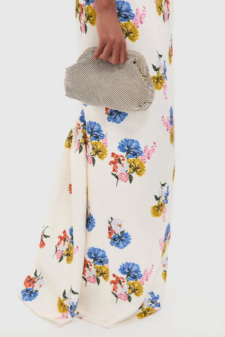 Woman in Retro Bouquet on White Fosette Gown, a classic, floor-length dress with a floral motif, styled with an effortless, high-end silver evening clutch.