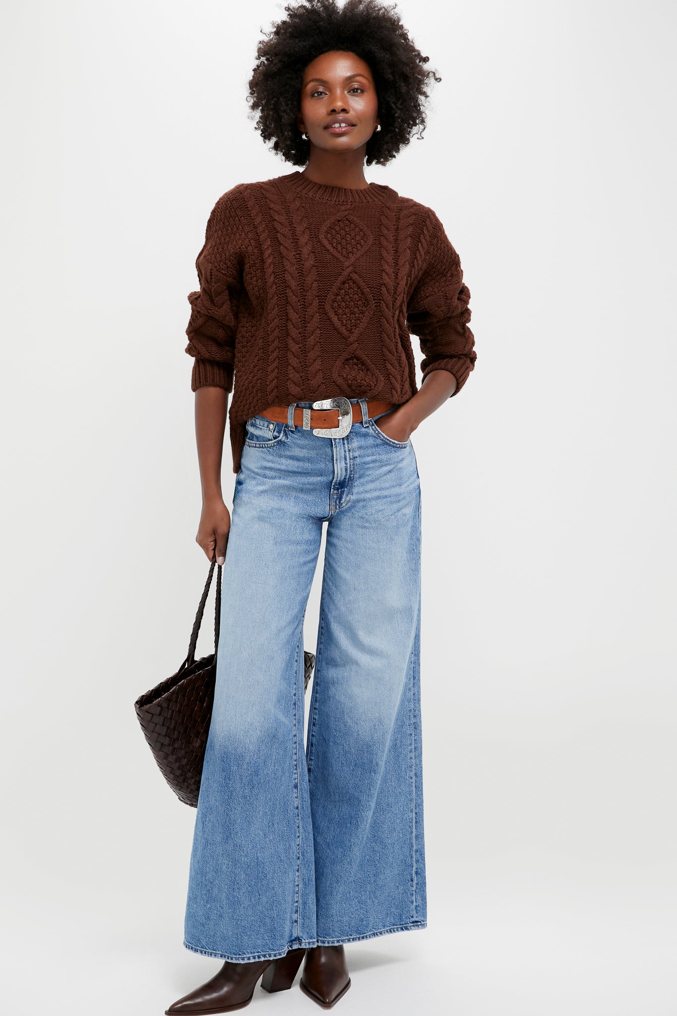 Woman in classic, chocolate-brown cable-knit sweater and wide-leg jeans, showcasing effortless style with Seal Brown Memphis Boots, featuring a sharp silhouette and sculpted heel.