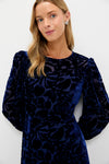 Young woman in the classic Navy Burnout Velvet Odette Maxi Dress, featuring blouson sleeves and velvet florals, embodying effortless, high-end style for fun occasions.