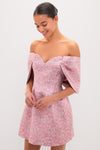 Young woman in a Pink Multi Jacquard Off-the-Shoulder Kara Midi Dress, smiling softly, showcasing an effortless, high-end look with classic, fun elegance.