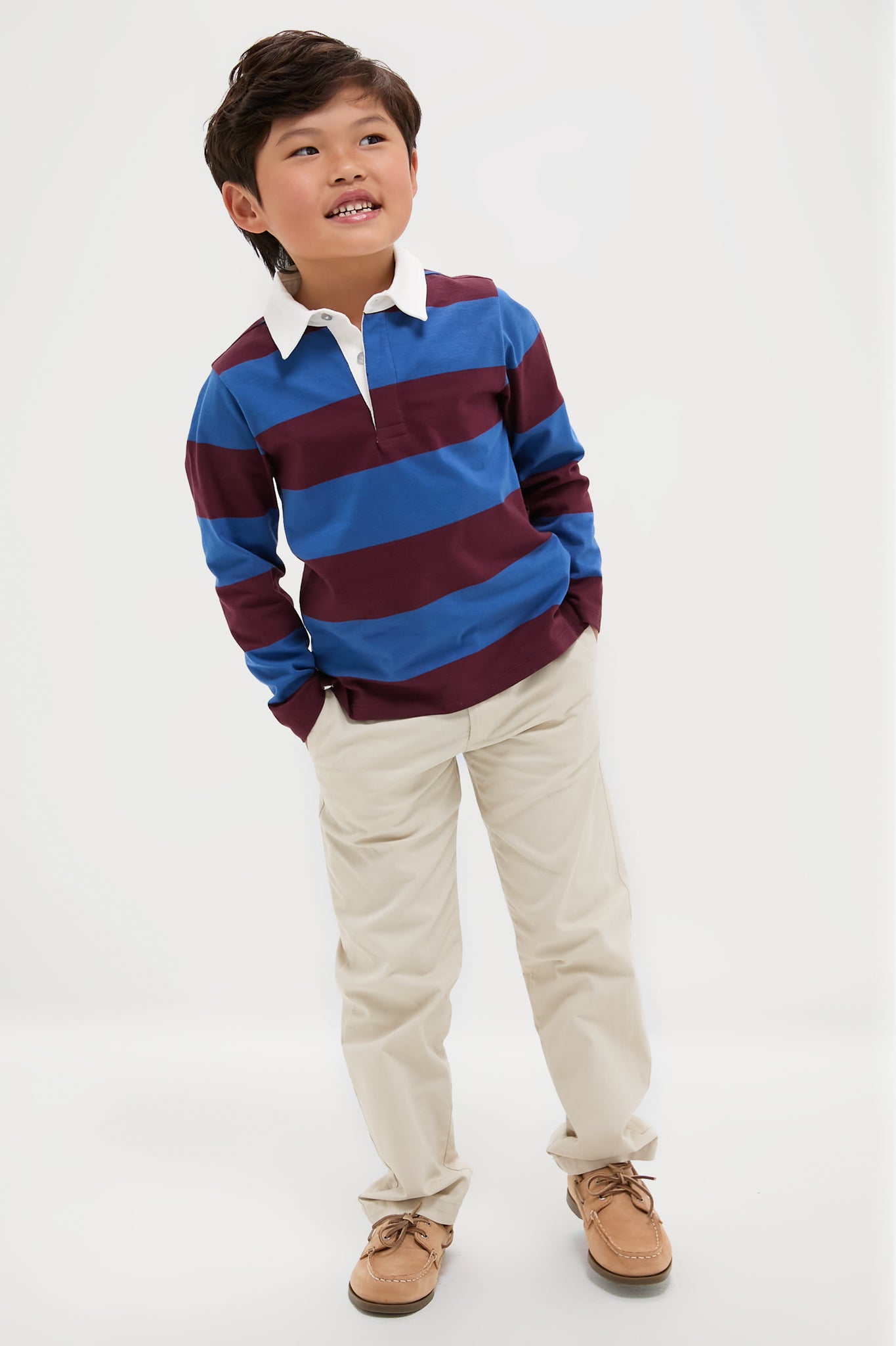 Young boy in a classic, effortless Petrol Blue Stripe Tijo Long Sleeve Boy Rugby Shirt, embodying a fun and high-end style, hands in pockets, relaxed pose.