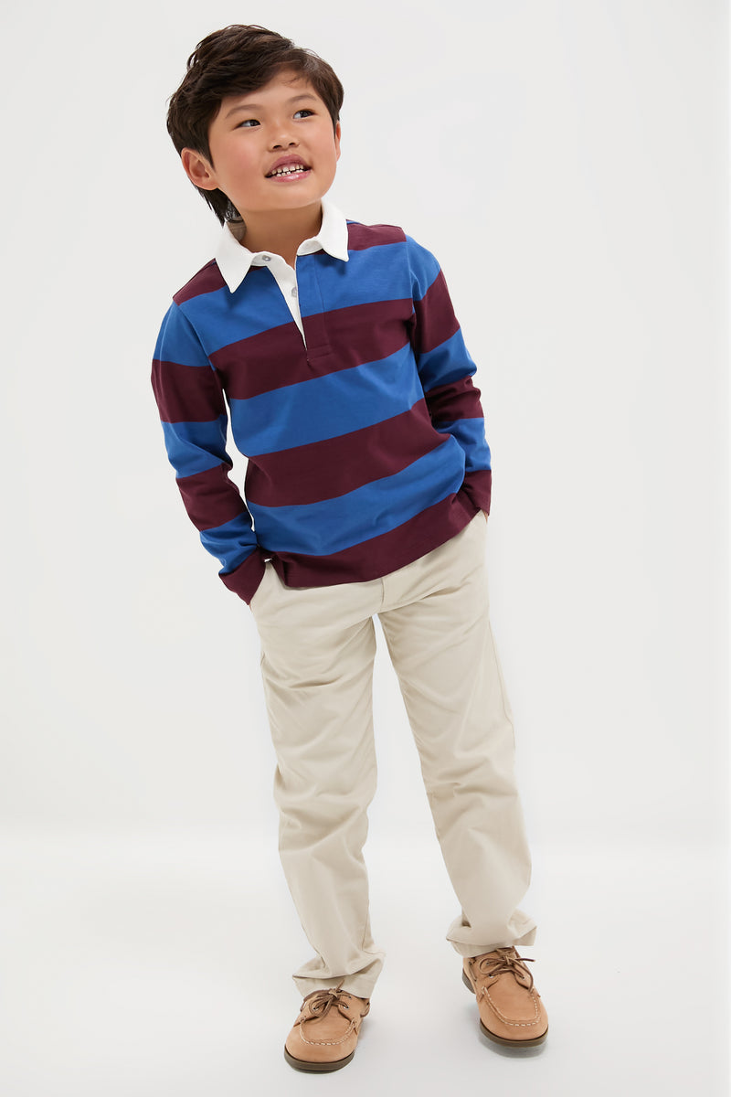 Young boy in a classic, effortless Petrol Blue Stripe Tijo Long Sleeve Boy Rugby Shirt, embodying a fun and high-end style, hands in pockets, relaxed pose.