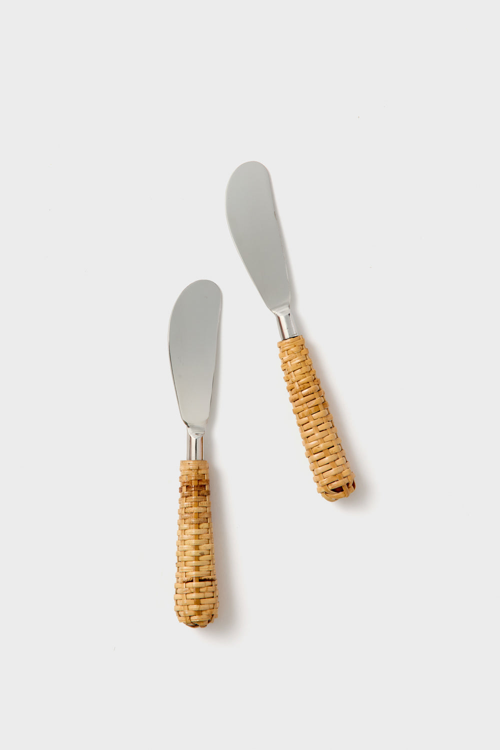 Two's Company butter knives feature rounded stainless steel blades and woven rattan handles, neatly arranged as a stylish set of two.