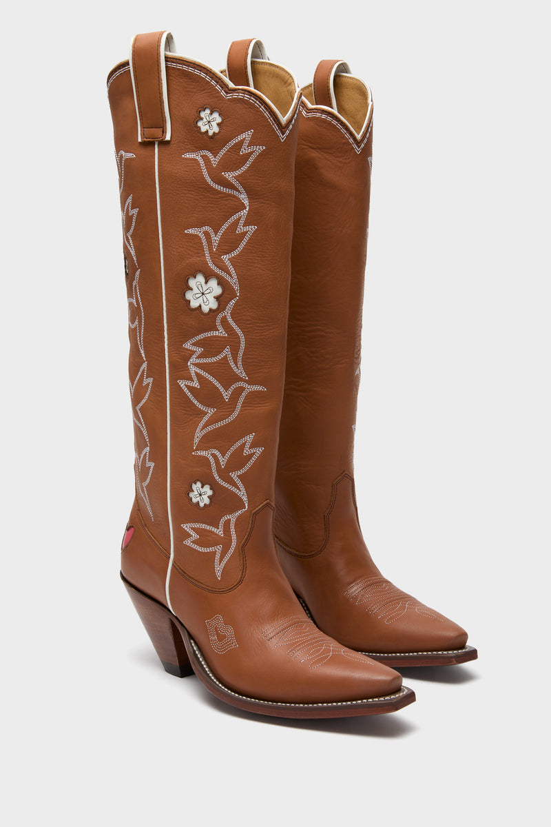 Sierra and White Honey Boots: Classic brown leather cowboy boots with effortless hummingbird embroidery and playful floral inlays, perfect for adding fun to high-end, versatile outfits.