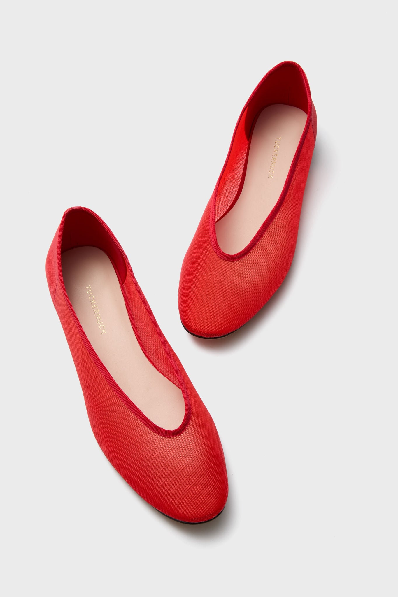 Chic red mesh flats, featuring a rounded closed-toe and minimal design, displayed on a light gray background—ideal for those seeking trendy women's footwear.