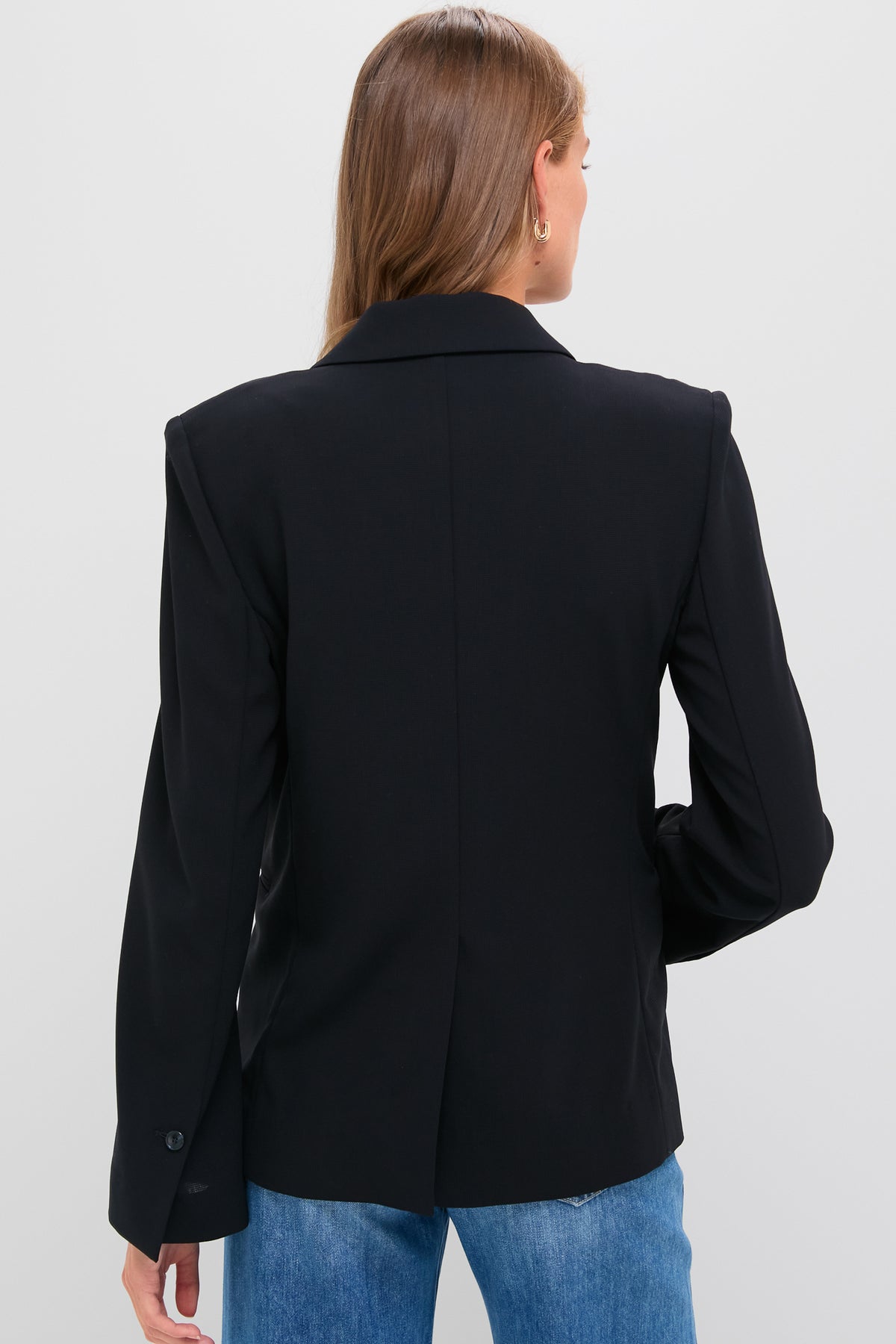 Back view of a person in the classic Midnight Boy Blazer, showcasing its relaxed fit and peak lapel, paired effortlessly with medium-blue denim jeans.