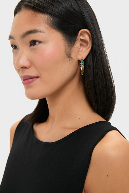 Woman wearing Berry Gem Medium Hoop Earrings - Malachite, featuring classic gold hoops adorned with green stones and crystals, embodying an effortless, high-end, and fun style.