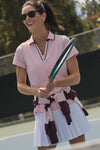 Woman on tennis court wearing Pink Short Sleeve Performance Jersey Caroline Polo, holding racket, ready to play. Classic, effortless style with high-end quick-dry fabric for fun activity.