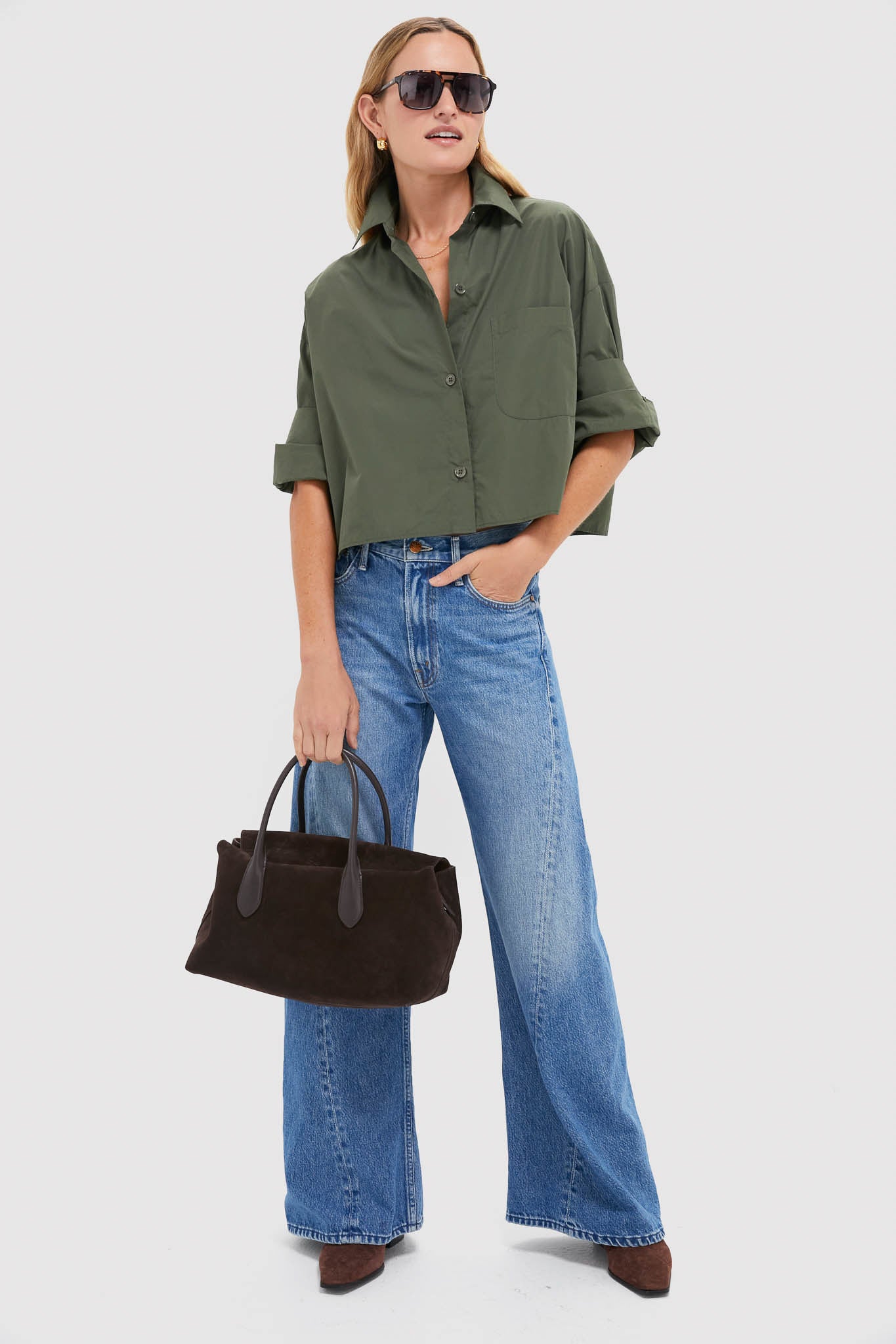 Woman wearing the Duffle Bag Next Ex Shirt, a classic, boxy cropped button-down, paired with wide-leg jeans and suede accessories for an effortless, high-end look.