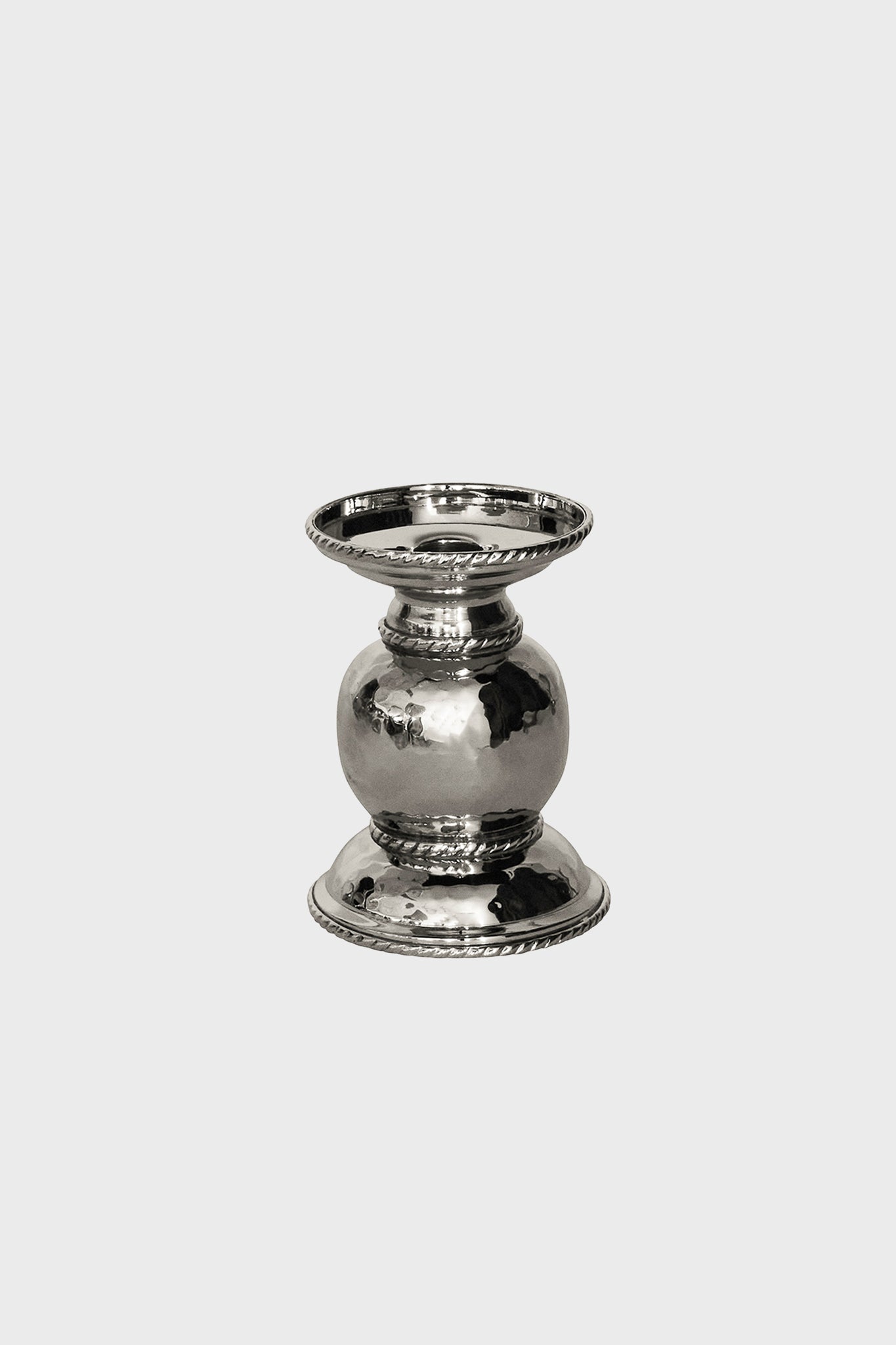 A small, polished silver candle holder with a rounded center, flat base, and decorative ridged edges—crafted in hammered stainless steel by Juliska for an elegant touch.