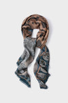 This Sabina Savage scarf is a luxe, lightweight wool-silk blend with animal prints and illustrative designs in brown, grey, and blue, finished with frayed edges.