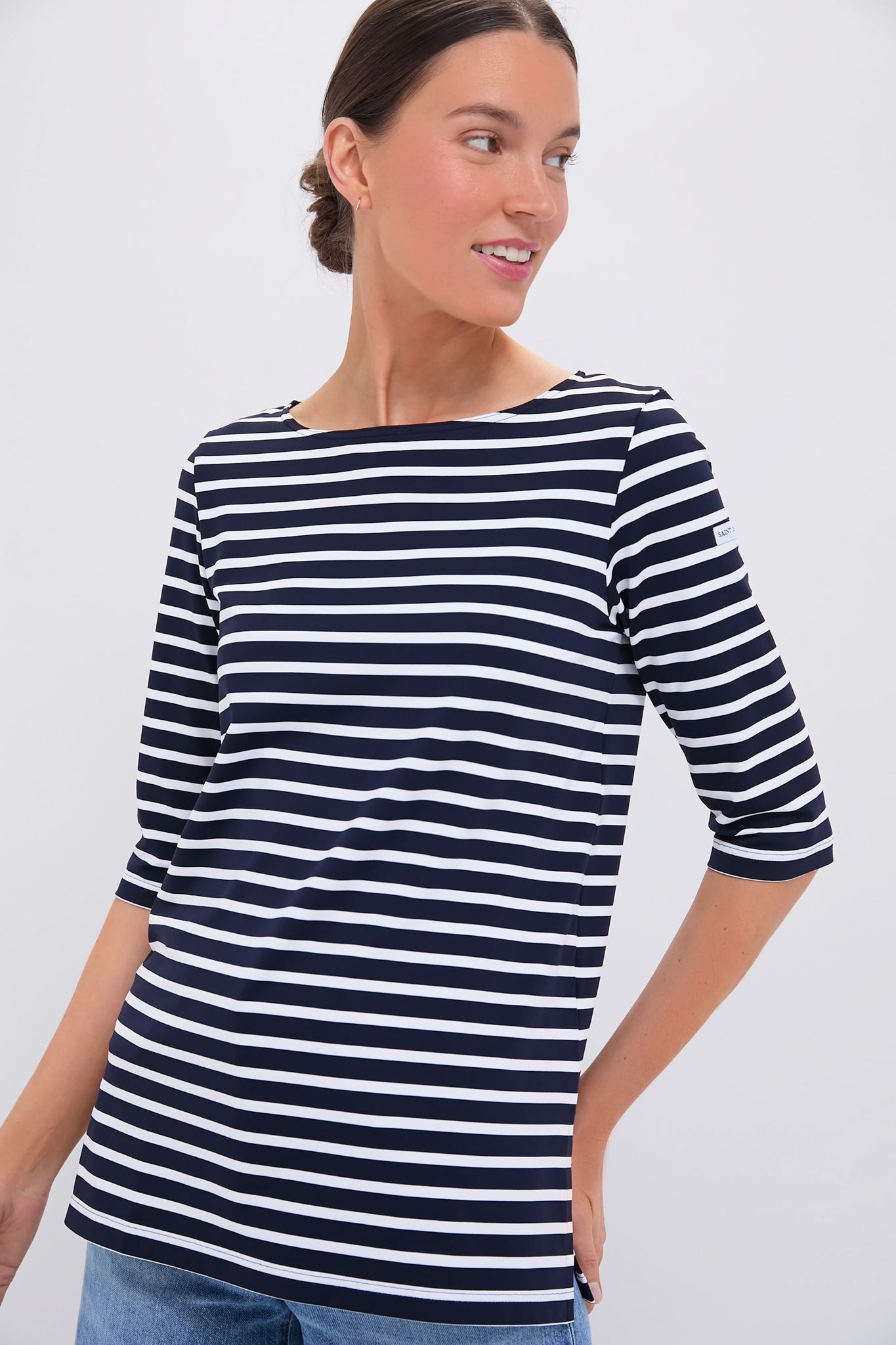 Woman in a Saint James navy and white boat neck top with three-quarter sleeves, featuring classic nautical stripes.
