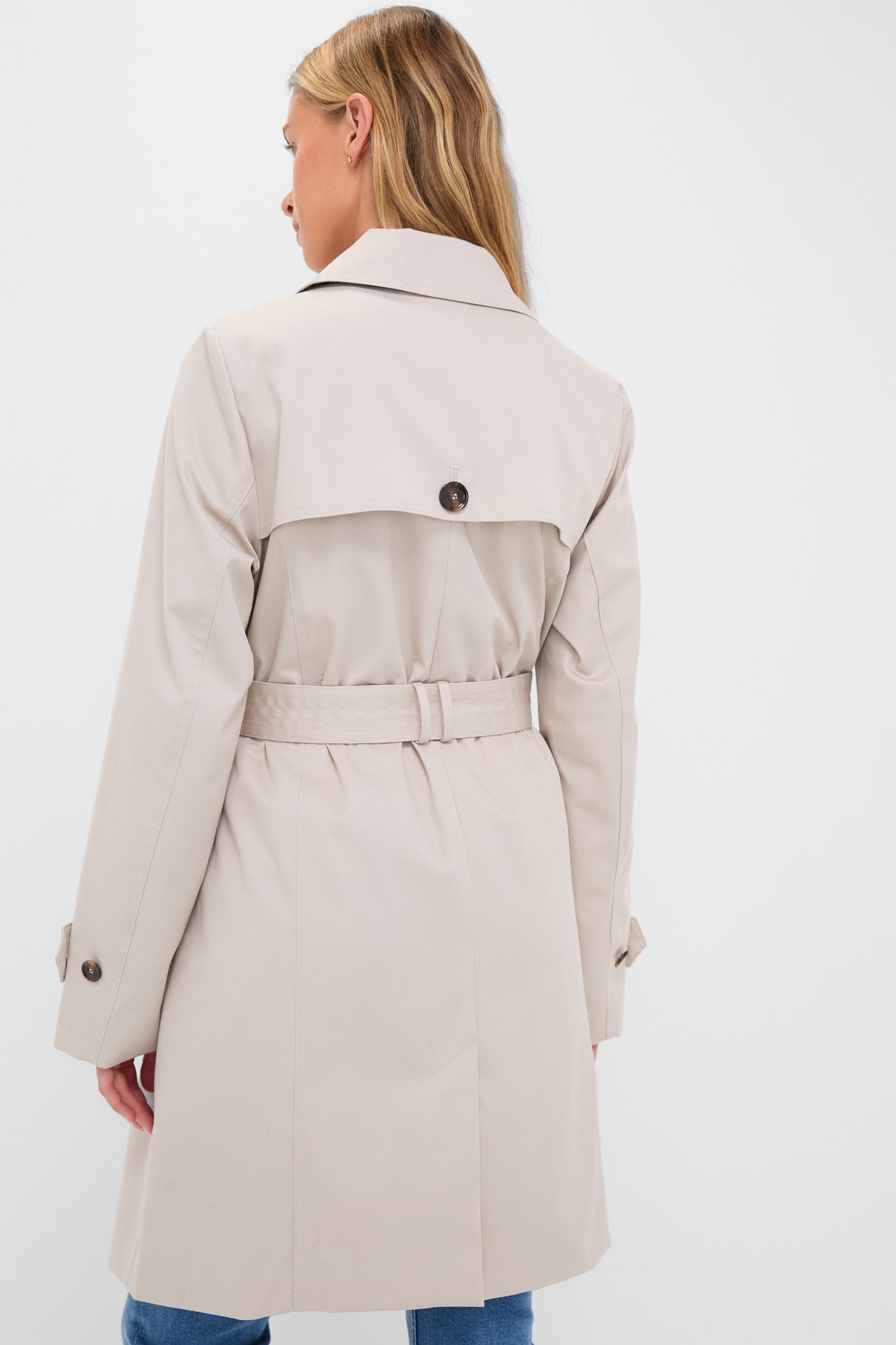 Back view of a person in a classic, high-end Mist Short Greta Showerproof Jacket, showcasing effortless style with a belted waist and buttoned storm flap.