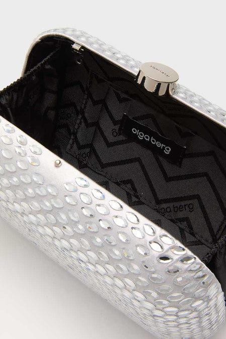 Close-up of an open Olga Berg evening bag with a silver textured, reflective exterior and black zigzag-patterned fabric lining with the Olga Berg label inside.