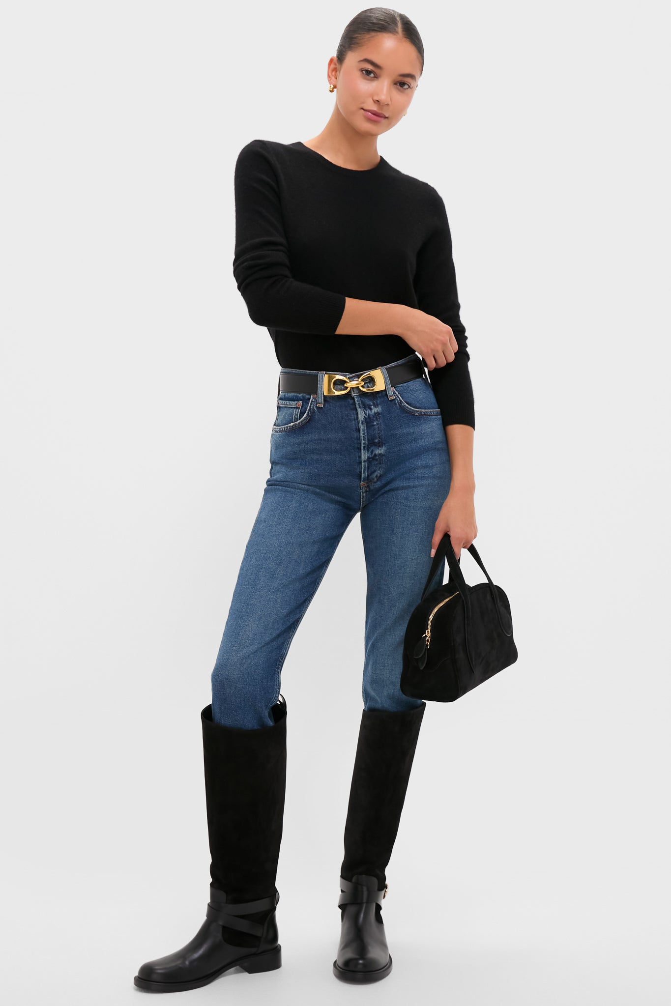 Woman models the Slick Riley Crop, showcasing a classic, effortless look with high-waisted jeans, suede boots, and a high-end, fun top-handle bag.