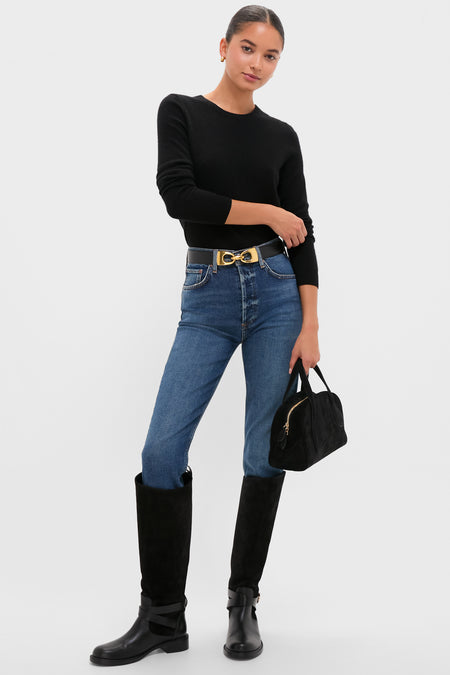Woman models the Slick Riley Crop, showcasing a classic, effortless look with high-waisted jeans, suede boots, and a high-end, fun top-handle bag.