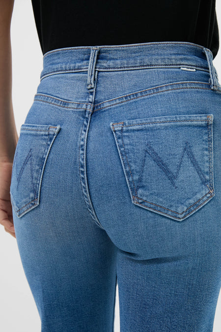 Person shown from the back wearing MOTHER high-rise straight leg jeans with visible back pockets and belt loops, paired with a black top. Crafted in stretch denim for all-day comfort.