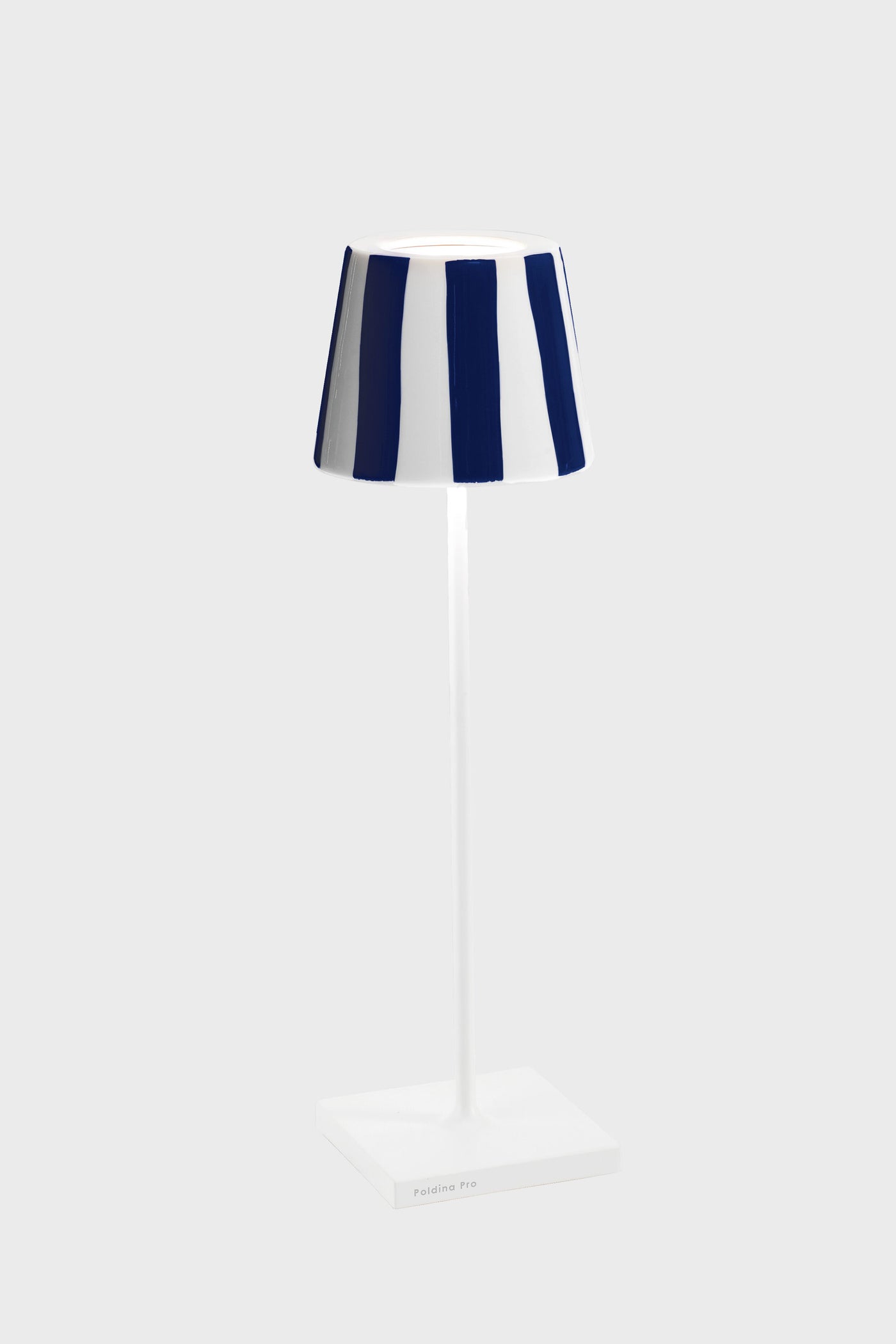 The Zafferano table lamp features Italian design with a slim white stand, square base, and a blue and white striped shade, inspired by the Poldina Pro style.