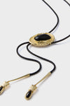 Gold and Black Dolly Bolo Tie Necklace: A classic, effortless accessory with a braided faux leather cord, gold-tone hardware, and striking black stone, adding fun, high-end flair to any outfit.