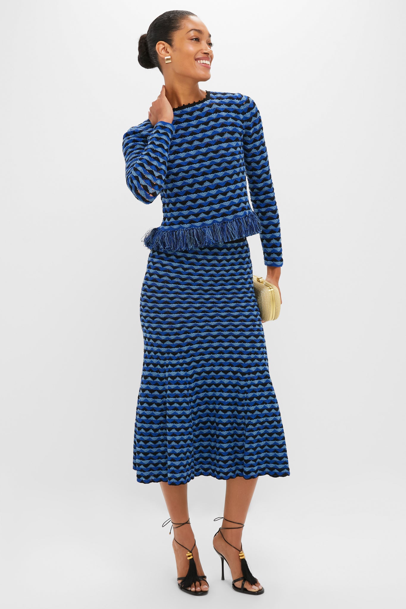 Woman models the classic Blue and Black Profundo Midi Skirt in a bold textured knit, paired with a matching top, exuding effortless style and high-end fun.