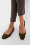 Person wearing Dark Olive Suede Nadia Flats with chic square toes and slip-on design, paired with leather-look pants, showcasing classic, effortless style for high-end everyday wear.