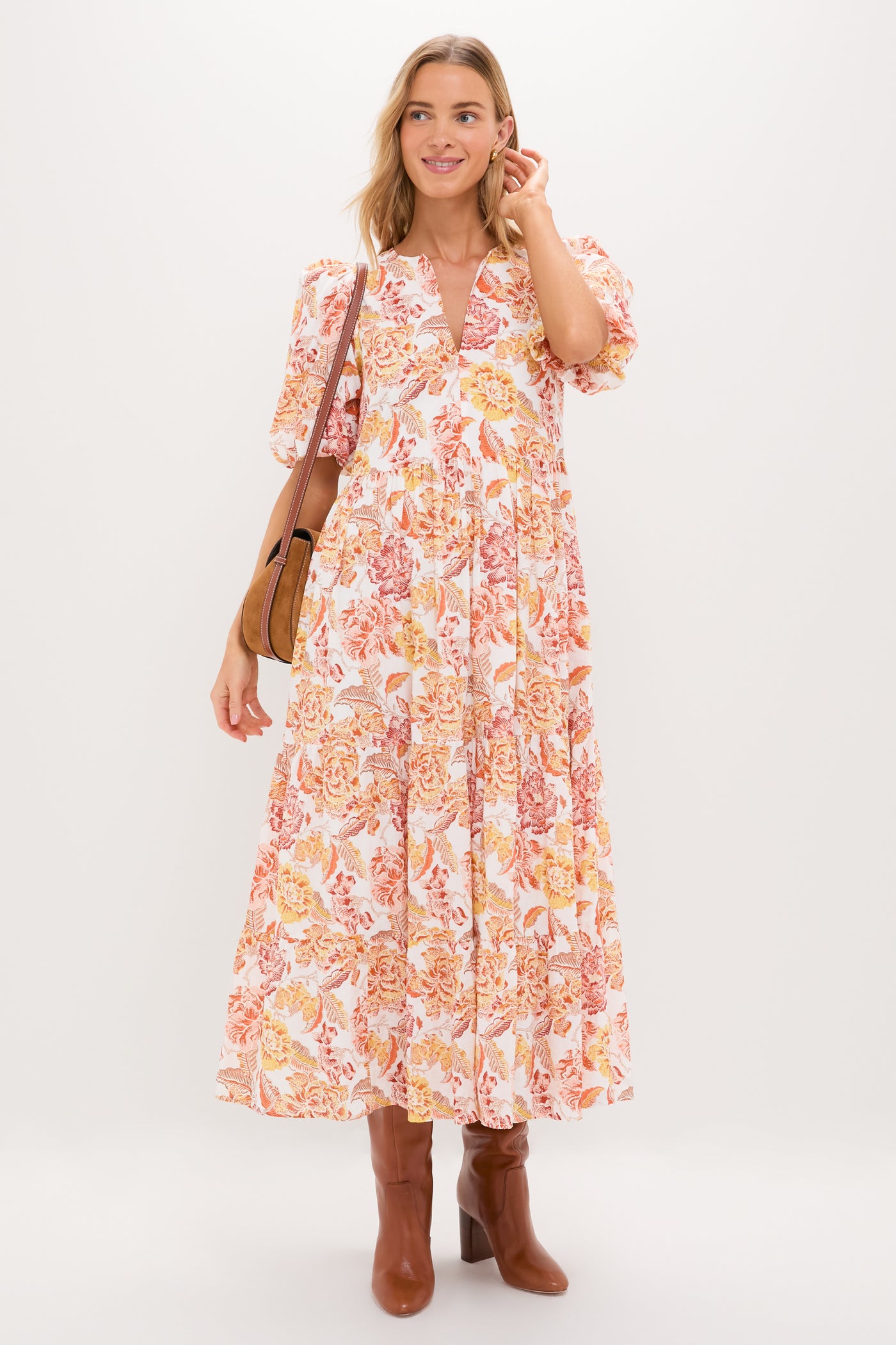 Woman in the Saffron Floral Cisco Maxi Dress, with classic puff sleeves and flowy silhouette, styled with a brown leather bag and boots, exuding effortless, high-end charm.