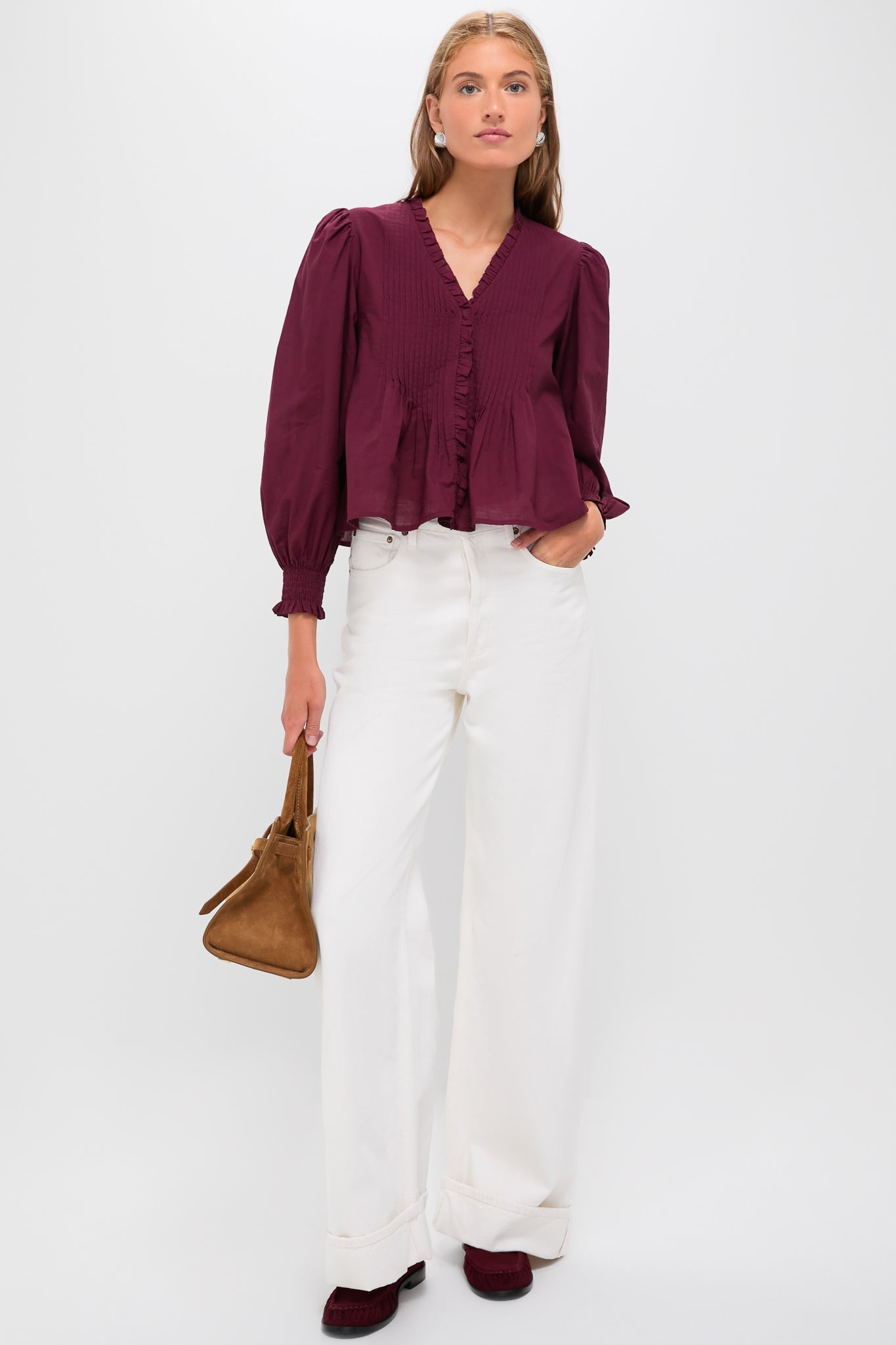 Model in classic, high-end Exclusive Burgundy Anise Long Sleeve Top with puff shoulders, peplum hem, and smocked cuffs, paired effortlessly with wide-leg white trousers.