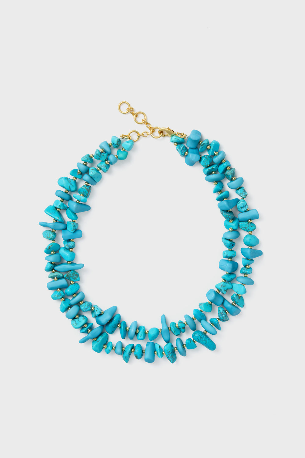 A turquoise double strand piece with irregular stones, small gold beads, and a gold plated brass clasp.