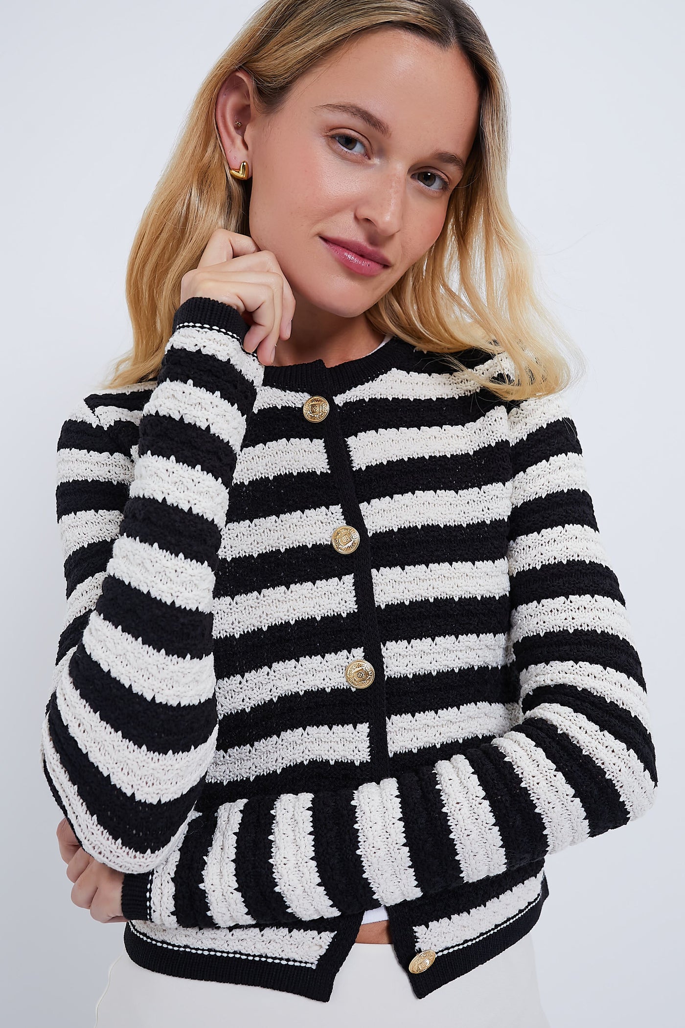 A woman with long blonde hair wears the Moon River Black and White Striped Cardigan, featuring a cropped hem and statement gold buttons.
