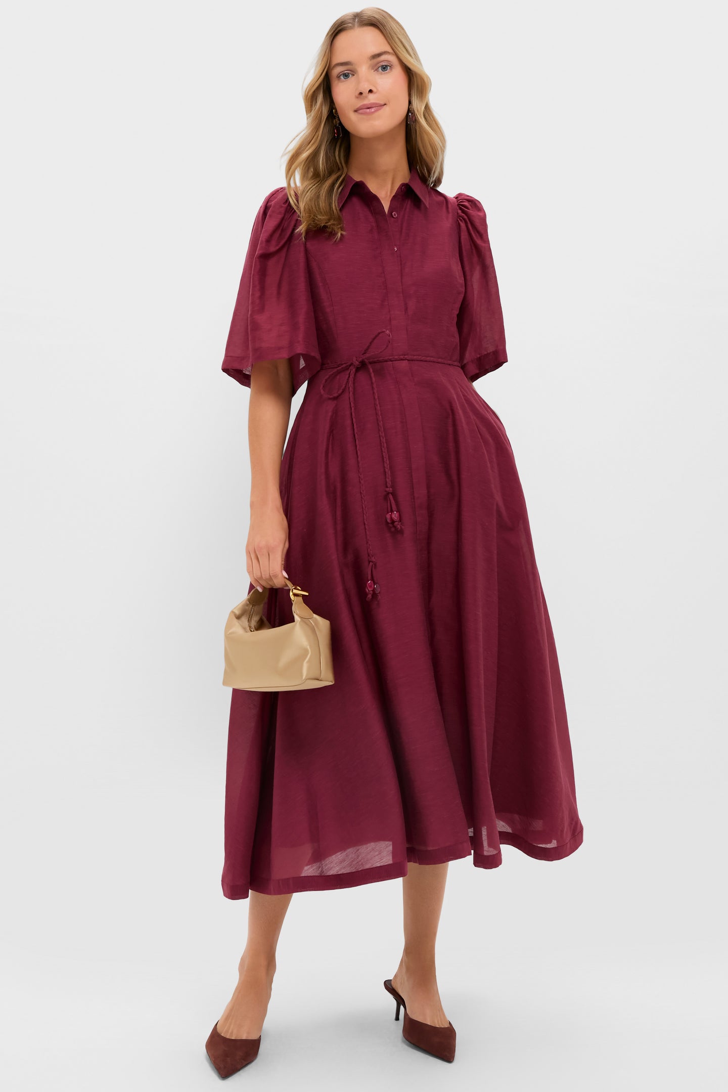 Model wearing the classic, effortless Oxblood Cindy Midi Dress with puff sleeves, braided belt, and beige handbag, embodying fun and high-end style.