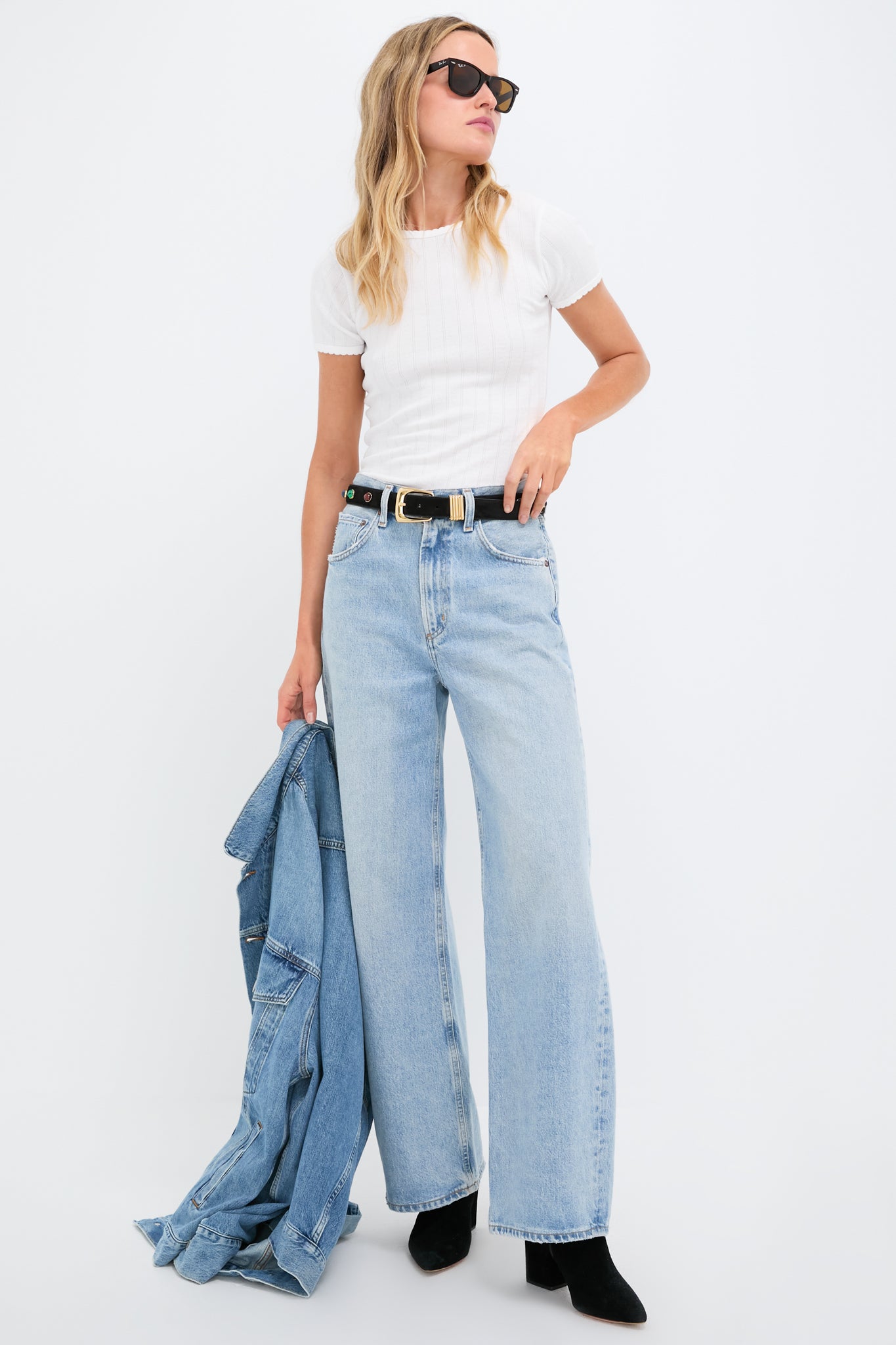 Woman models an effortless, classic look featuring the Black Stone Embellished Harness Belt with gold buckle and semi-precious stones, paired with casual jeans and boots.