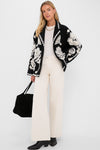 Model in a classic Black Cream Floral Arabesque Fleece Coat, showcasing an effortless, high-end style with wide-leg trousers and a chic tote.