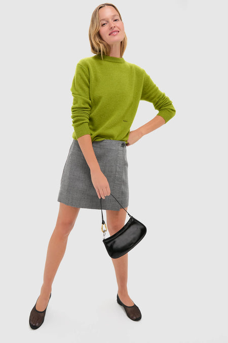 Model wearing Heathered Grey Marta Mini Skirt, a classic, effortless wool piece with wrap detail, paired with a chartreuse sweater and black flats for a high-end, fun look.