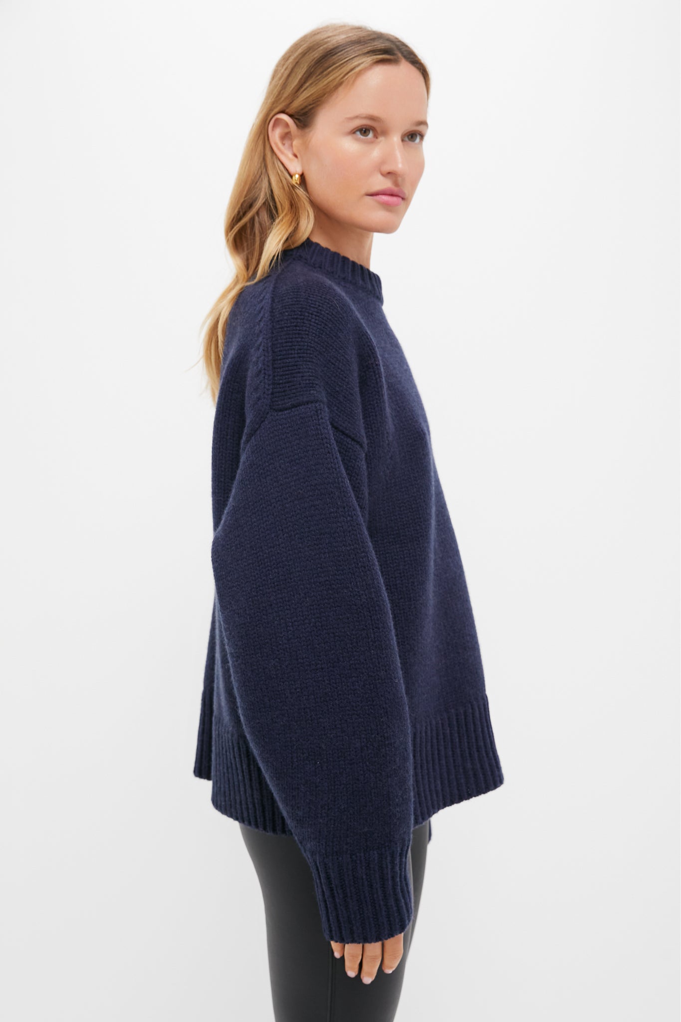 Young woman in profile wearing a classic Navy Genevieve Cashmere Wool Blend Crewneck Sweater, showcasing its effortless, high-end boxy fit and ribbed finishes.