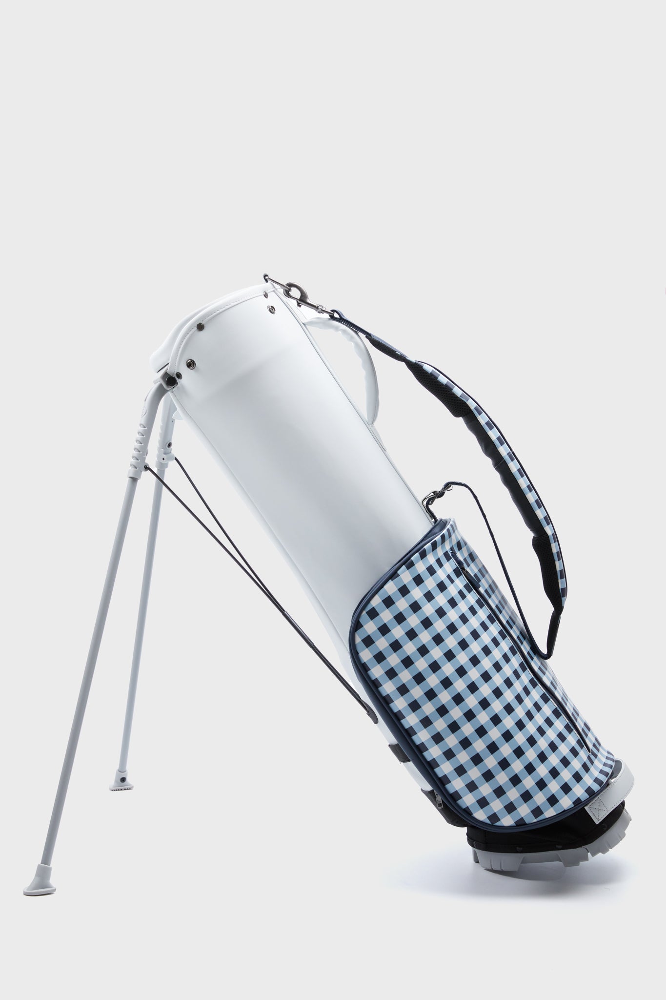 A Tuckernuck x Stitch Golf MIY SL2 White Gingham bag features a blue and white checkered side pocket, a matching shoulder strap, and stands upright on its extendable legs.