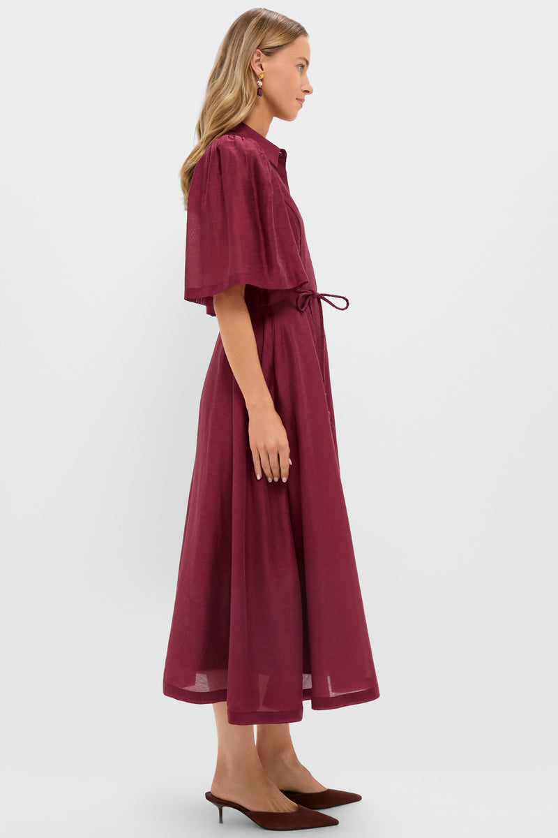 Woman in profile wearing the classic Oxblood Cindy Midi Dress with puff sleeves and a waist tie, styled effortlessly with statement earrings and matching mule shoes.