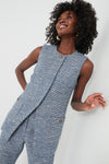 A woman smiles warmly in a sleeveless, textured blue Tuckernuck Dorset Tweed Delphine Top with matching pants.