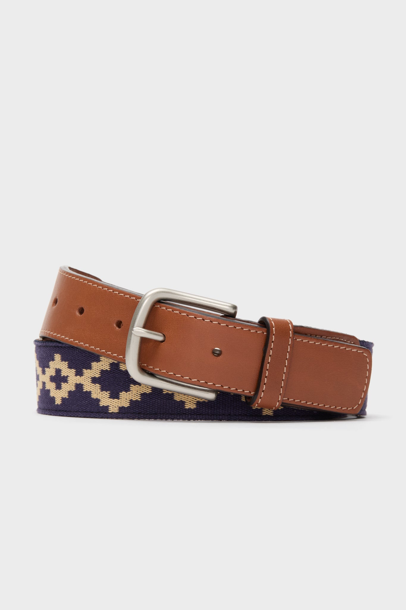 La Matera brown vegetable-tanned leather belt with a brass buckle and navy Argentine woven fabric featuring a beige geometric pattern.