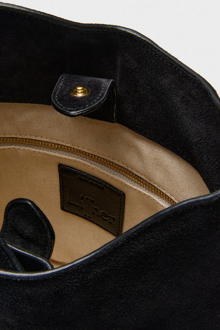 Black Suede Belted Bucket Bag interior with beige canvas lining, gold-tone zipper pocket, magnetic snap, and “Liner” label, highlighting classic, effortless, and high-end design.