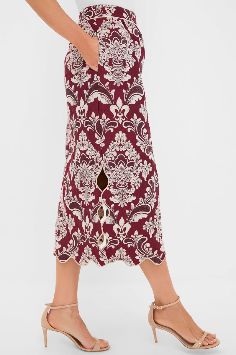 Woman modeling the Blush Pink and Burgundy Bicolor Jacquard Waves Midi Skirt with a scalloped hem and side pockets, paired with beige strappy stilettos for an effortless, high-end look.
