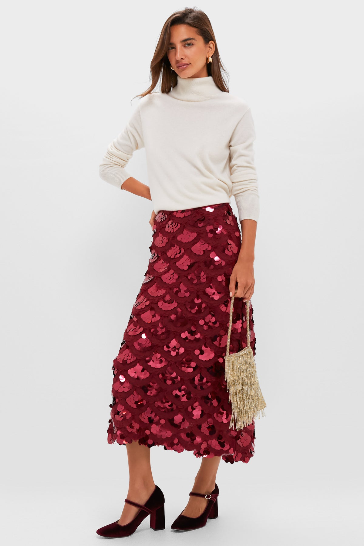 Model in a classic look, showcasing Oxblood Velvet Julia Heels with a block heel and strap, paired effortlessly with a sequined skirt and fringe handbag for a fun, high-end style.