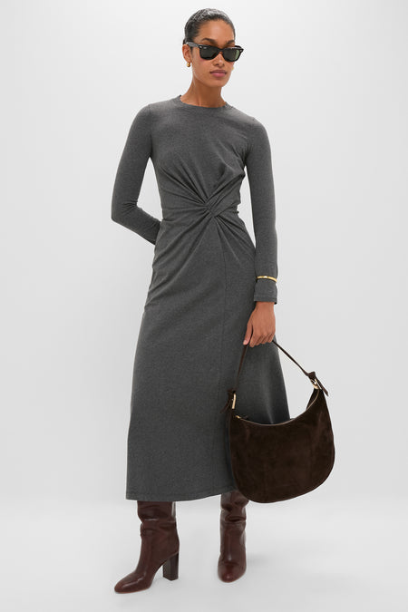 Woman styled in classic elegance with a Tmoro Suede with Gold Morgan Shoulder Bag, showcasing effortless sophistication with knee-high boots and minimal gold accessories against a light-gray backdrop.