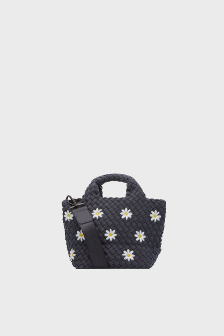 A small black Naghedi handbag from the St. Barths Petite Daisy collection, featuring white and yellow daisy appliqués, a short handle, and an adjustable strap. This chic neoprene tote is both stylish and versatile.