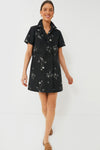 A woman wears the Tuckernuck Black Meadow Rue Marley Dress, an oversized shirt dress featuring a beautiful floral print.