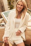 Shea McGee wearing an oversized white blazer, white tank, and shorts