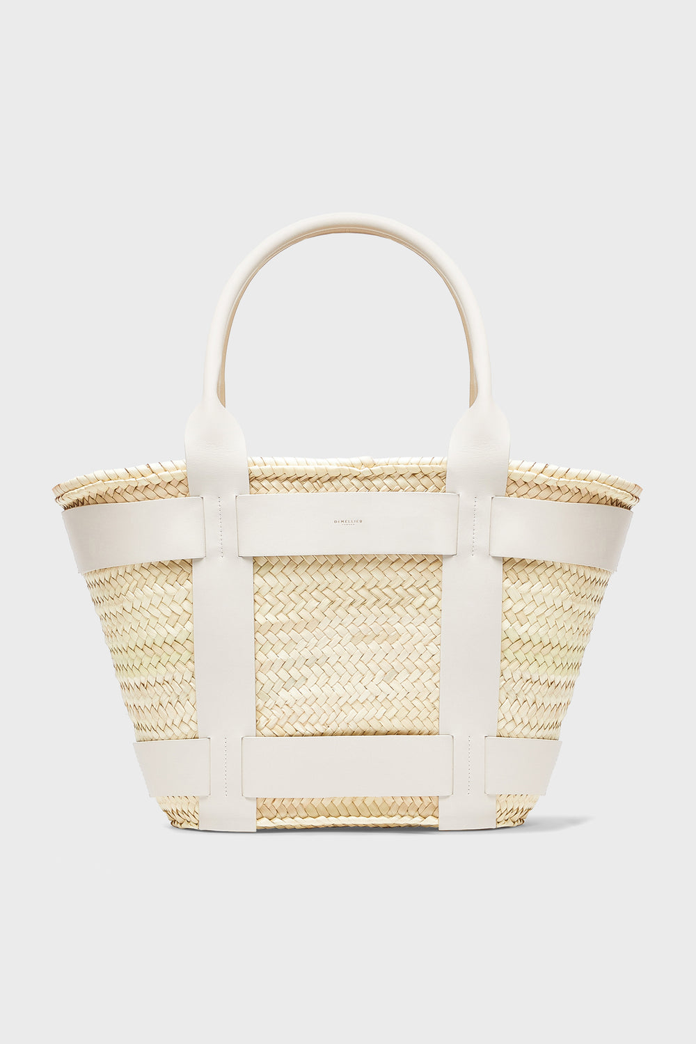 The Demellier Santorini Bag is a woven straw handbag with white leather handles and trim, ideal for those who love handcrafted accessories.