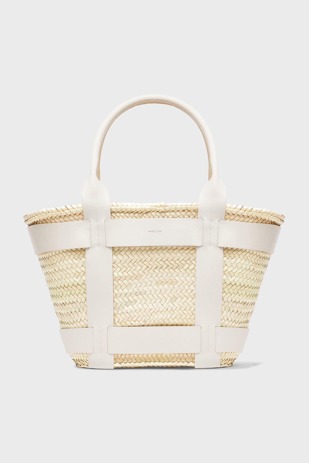 The Demellier Santorini Bag is a woven straw handbag with white leather handles and trim, ideal for those who love handcrafted accessories.