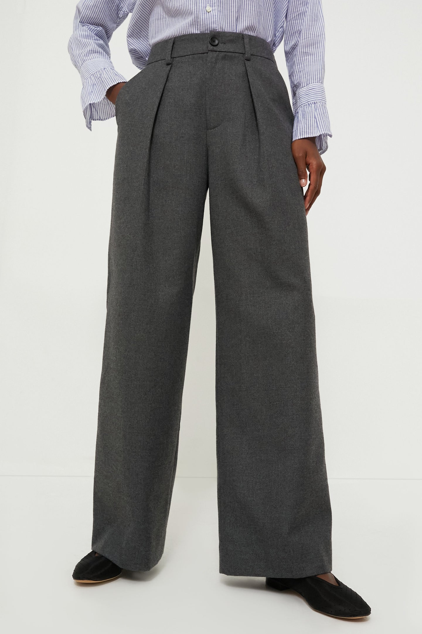 A person wearing Alex Mill high-waisted, wide-leg gray wool trousers, a blue and white striped shirt, and black shoes for a relaxed fit look.