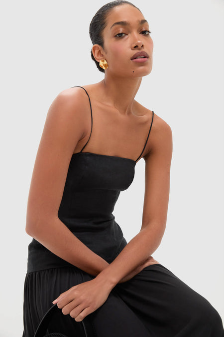 Woman in a classic Black Lenise Maxi Dress with fitted bodice and flowing skirt, accessorized with a chunky gold earring, exuding an effortless, high-end elegance.